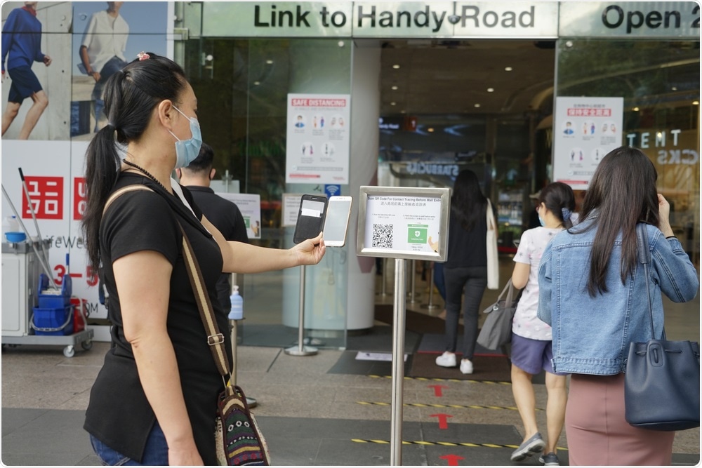 Singapore - June 20, 2020: A woman scans a contact tracing QR code before entering a mall on the second day shops reopen during Phase 2 after Singapore