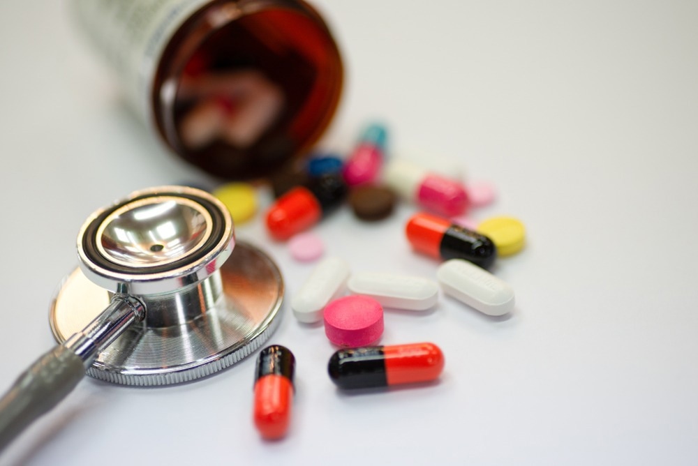 Close up of statin and beta-blocker pills and capsules with bottle and stethoscope