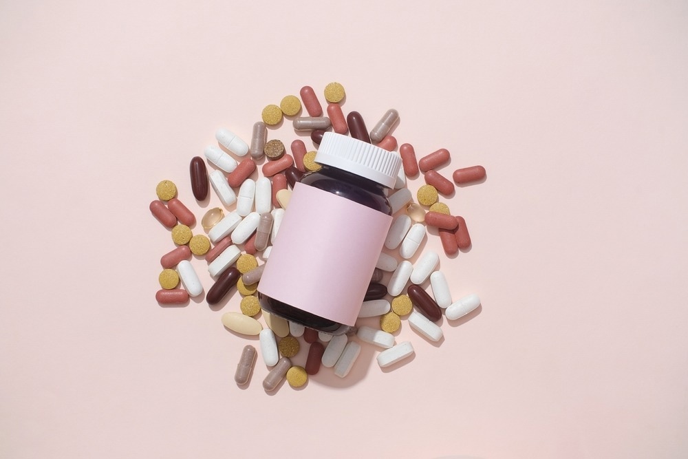 An empty medicine bottle without a label is displayed amidst a pastel pink background.