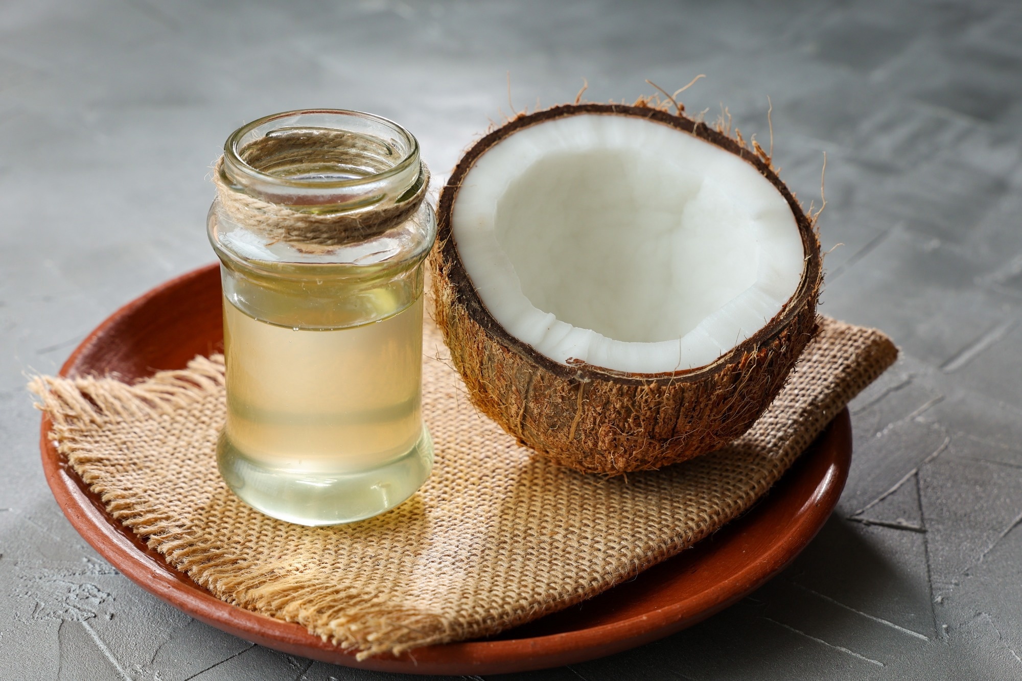 Coconut Oil in glass jar with Coconut cut open in half.