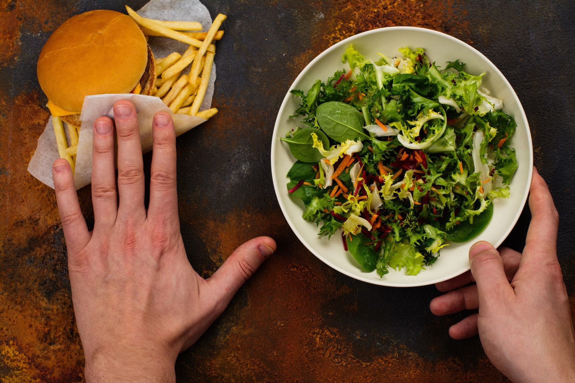 Young man making choice between salad and fast food