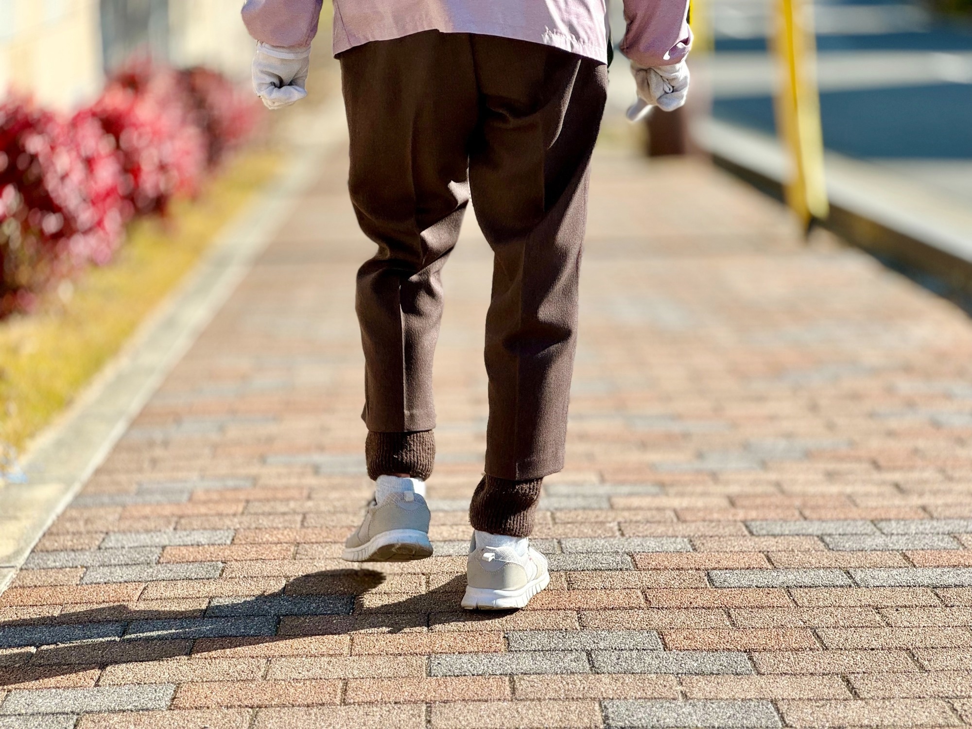 The feet of an elderly woman walking on the sidewalk