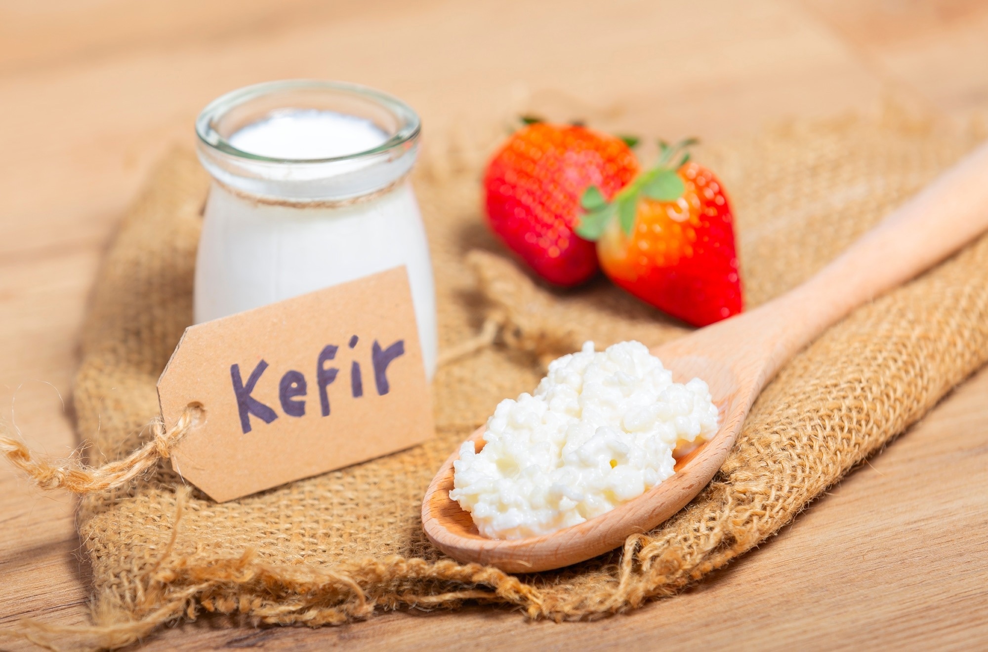 Kefir grains in wooden spoon in front of cups of Kefir Yogurt Parfaits.